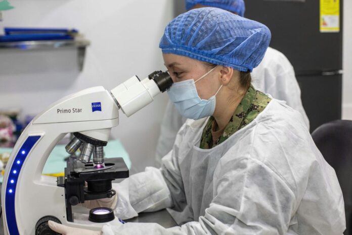 Ilmuwan melihat melalui mikroskop di laboratorium.